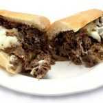 A plate featuring a delectable half of a cheesesteak sub from Genova's To Go. Pure sandwich perfection!
