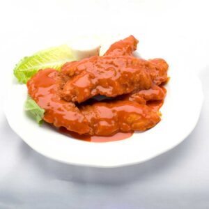 Delicious buffalo tenders on a plate, drizzled with sauce and topped with fresh lettuce from Genova's To Go.