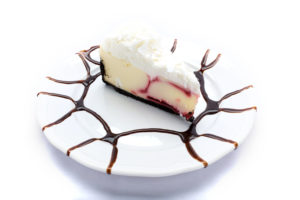 Indulge in a slice of creamy strawberry cheesecake by Genova's To Go, placed on a white plate.