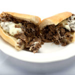 A plate featuring a delectable half of a cheesesteak sub from Genova's To Go. Pure sandwich perfection!