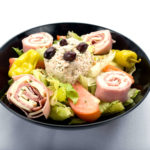 A delightful bowl of Chef salad Genova's To Go, filled with mouthwatering meat, cheese, and vibrant veggies.