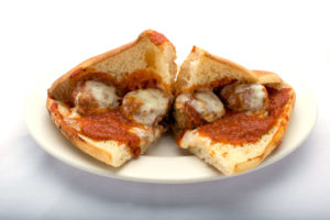 A delicious meatball sub from Genova's To Go - a plate with a sandwich filled with meatballs and cheese.