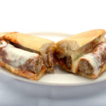 A delicious sausage parmigiana sub with melted mozzarella from Genova's To Go, served on a plate.
