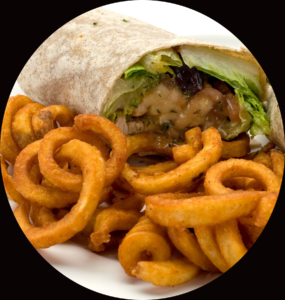 Close up of the Chicken Cesar Wrap made with romaine lettuce, fresh tomatoes, olives and grilled chicken from Genova's To Go. Served with a side of curly fries.