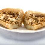 A mouthwatering chicken cheesesteak sandwich on a plate - Genova's To Go's specialty!