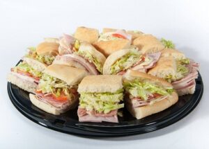Ham and cheese sandwiches on a black plate, served on a sub tray from Genova's To Go. Delicious lunch option!