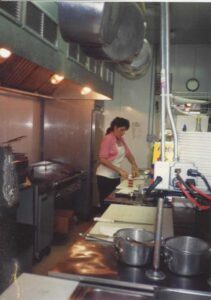 Vintage image of Genova's To Go cook preparing food in the kitchen.