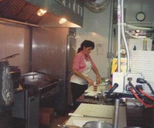 Vintage image of Genova's To Go cook preparing food in the kitchen.