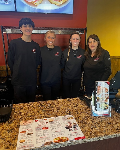 A picture of four Genova's To Go team members working behind the counter.